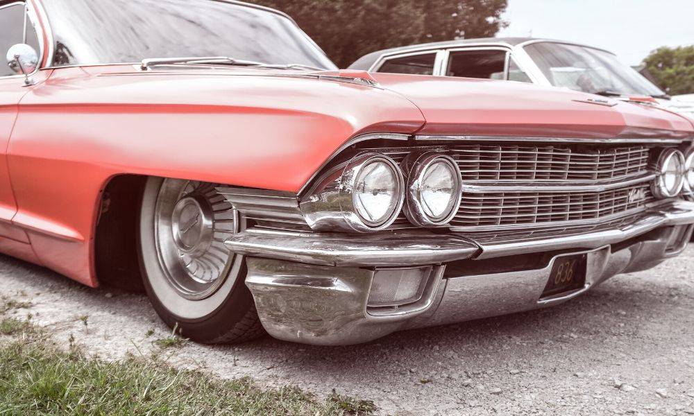 A restored, vintage red car parked in a grassy parking lot.